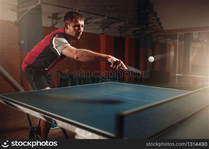 Man and woman playing ping pong indoors, focus on racket. Couple in sportswear plays table tennis in gym. Man and woman playing ping pong, focus on racket