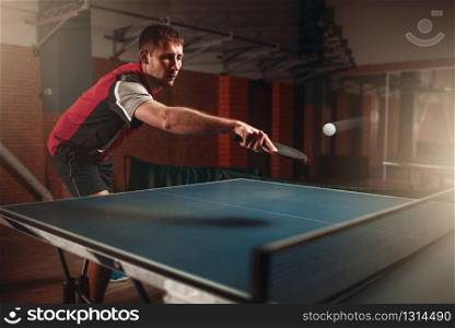 Man and woman playing ping pong indoors, focus on racket. Couple in sportswear plays table tennis in gym. Man and woman playing ping pong, focus on racket