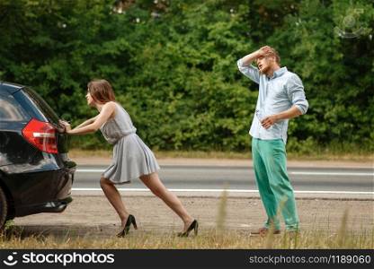 Man and woman pushing broken car on road, breakdown. Crashed automobile or emergency accident with vehicle, trouble with engine on highway