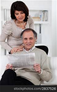 Man and woman reading newspaper