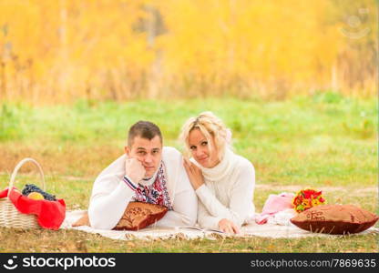man and woman relaxing comfortably on the plaid in the park
