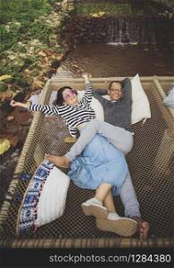 man and woman relaxing with happiness emotion on net cradle over flowing creek