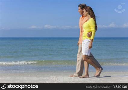 Man and woman romantic couple in colorful clothes walking on a deserted tropical beach with bright clear blue sky