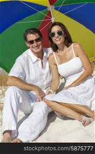 Man and woman romantic couple under a multi colored sun umbrella or parasol on a beach