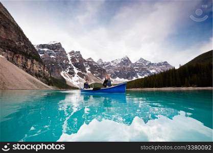 Man and woman sailing on peaceful lake against mountain range