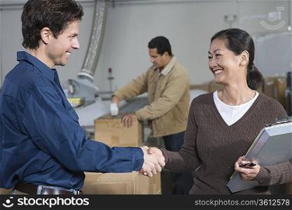 Man and woman shaking hands in distribution warehouse