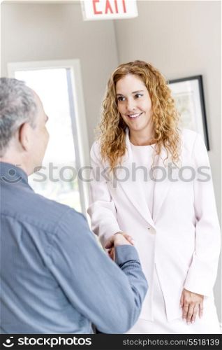 Man and woman shaking hands in office. Man and woman meeting in office shaking hands completing business deal