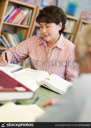 Man and woman sitting in library reading books (selective focus)
