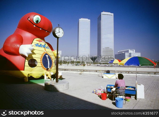 Man and woman sitting near an inflatable cartoon, Twin Towers, Osaka, Japan