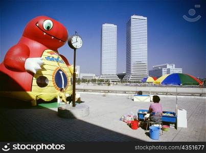 Man and woman sitting near an inflatable cartoon, Twin Towers, Osaka, Japan