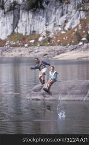 Man And Woman Skipping Rocks In A Mountain Stream