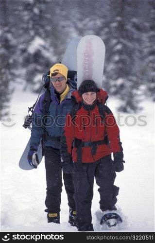 Man and Woman Snowshoeing With Snowboards