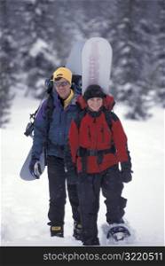 Man and Woman Snowshoeing With Snowboards