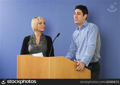 Man and woman speaking from lectern
