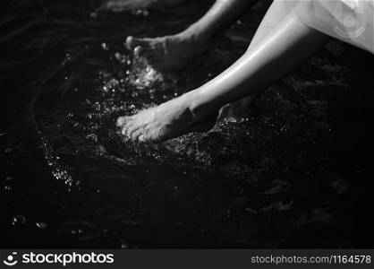 Man and woman stand with their feet in the water in the river close-up. Man and woman stand with their feet in the water in the river