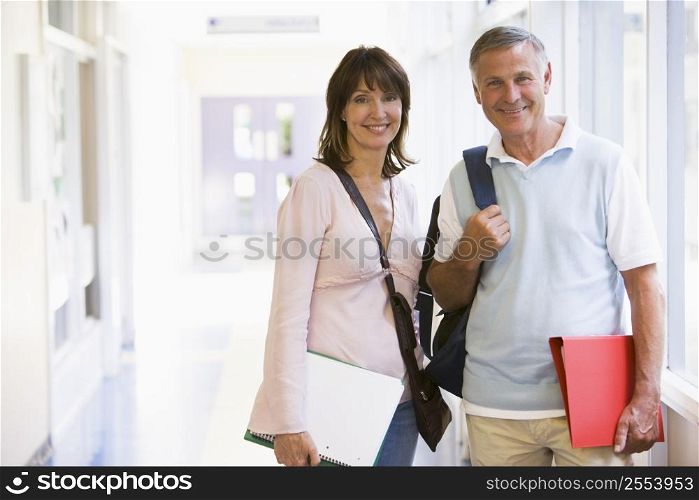 Man and woman standing in corridor with books (high key)