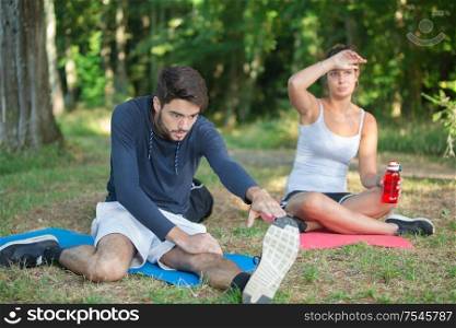 man and woman stretching legs in a park