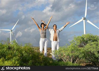 Man and woman stretching near wind turbines