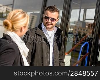 Man and woman talking waiting for bus smiling friends commuters