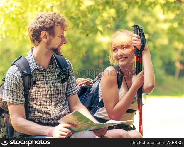 Man and woman tourists backpackers reading map on forest trip while resting. Couple hikers searching looking for direction guide. Backpacking summer vacation adventure..
