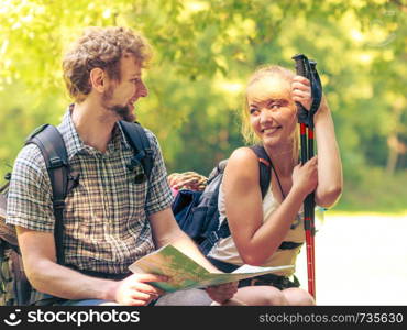 Man and woman tourists backpackers reading map on forest trip while resting. Couple hikers searching looking for direction guide. Backpacking summer vacation adventure..