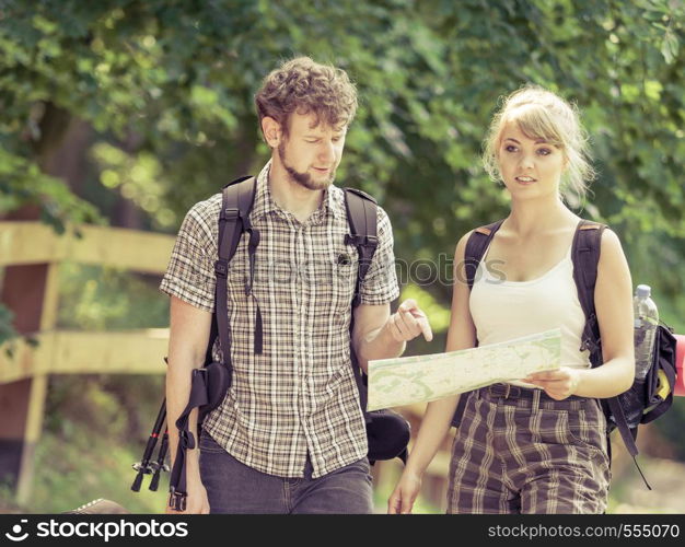 Man and woman tourists backpackers reading map on trip. Young couple hikers searching looking for direction guide. Backpacking summer vacation travel.