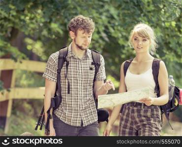 Man and woman tourists backpackers reading map on trip. Young couple hikers searching looking for direction guide. Backpacking summer vacation travel.