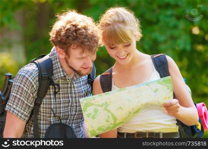 Man and woman tourists backpackers reading map on trip. Young couple hikers searching looking for direction guide. Backpacking summer vacation travel.