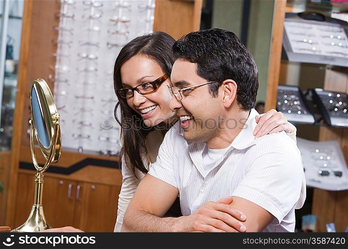 Man and woman trying on eyeglasses in store