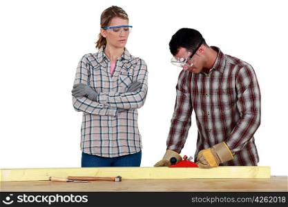 Man and woman using wood plane