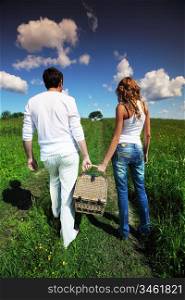 man and woman walk on picnic in green grass