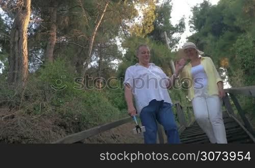 Man and woman walking in forest and taking selfie, using selfie stick. Evening.