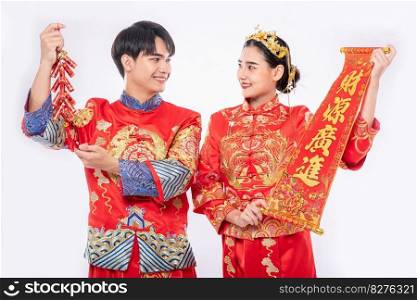 Man and woman wear Cheongsam suit celebrate chinese new year with chinese greeting card and firecracker together