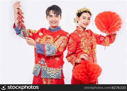 Man and woman wear Cheongsam suit celebrate chinese new year with red l&and firecracker 