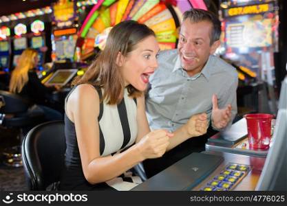 Man and woman winning casino slot machine