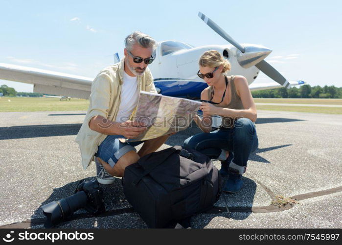 man and woman with camera looking at map in airfield