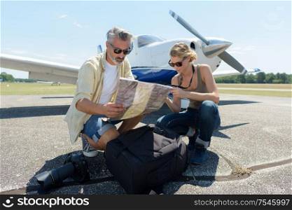 man and woman with camera looking at map in airfield