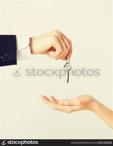 man and woman with house keys. picture of man hand passing house keys to woman