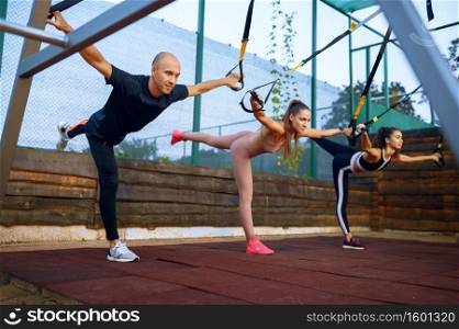Man and women doing exercise on sports ground outdoors, group fitness training. Athletes in sportswear, team fit workout, teamwork. Man and women doing exercise, group training