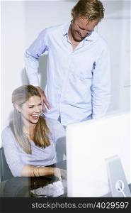 Man and women in office at computer.