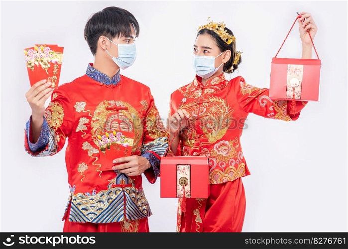 Man and women wear mask and cheongsam with holding red gift money and red bag