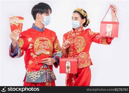 Man and women wear mask and cheongsam with holding red gift money and red bag