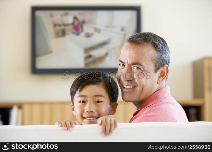 Man and young boy in living room with flat screen television smiling