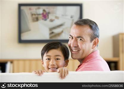 Man and young boy in living room with flat screen television smiling