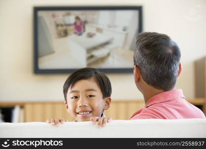 Man and young boy in living room with flat screen television smiling