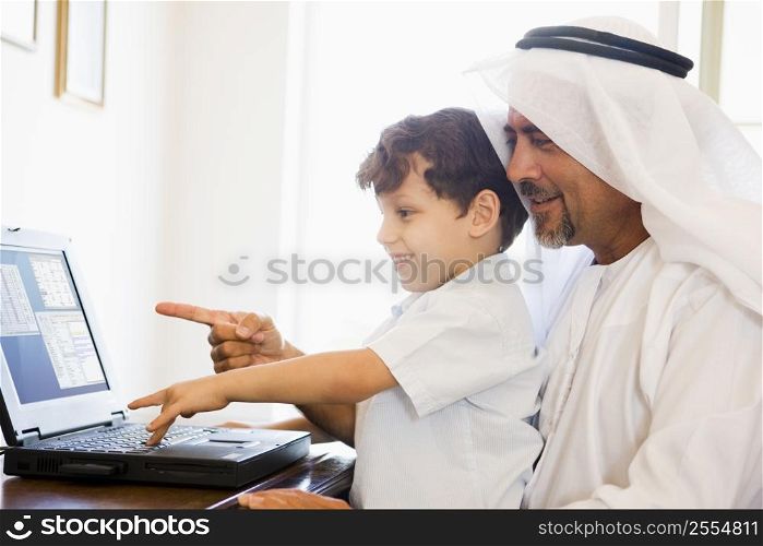 Man and young boy in office with laptop pointing and smiling (high key/selective focus)