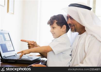 Man and young boy in office with laptop pointing and smiling (high key/selective focus)
