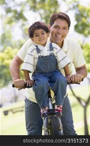 Man and young boy on a bike outdoors smiling