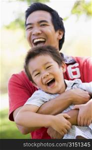 Man and young boy outdoors embracing and smiling