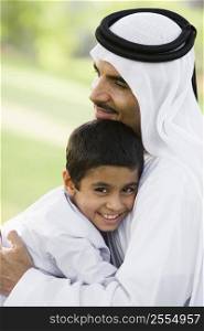 Man and young boy outdoors in park embracing and smiling (selective focus)